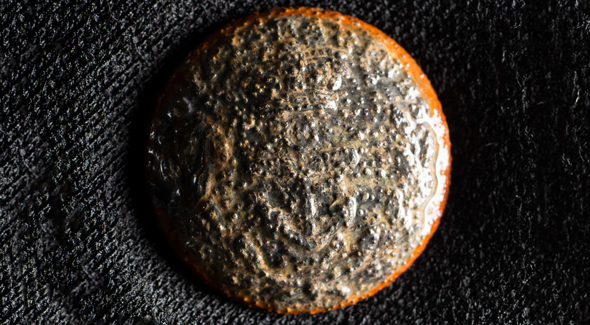 Un bouton rond gris avec des bords bruns.