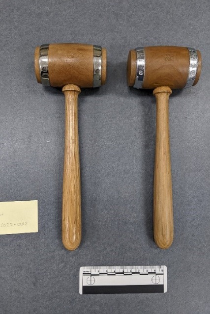 Deux maillets en bois présentés côte à côte, dont l'une est une reproduction et l'autre l'original. Les deux objets se ressemblent en forme, en couleur et en texture.
