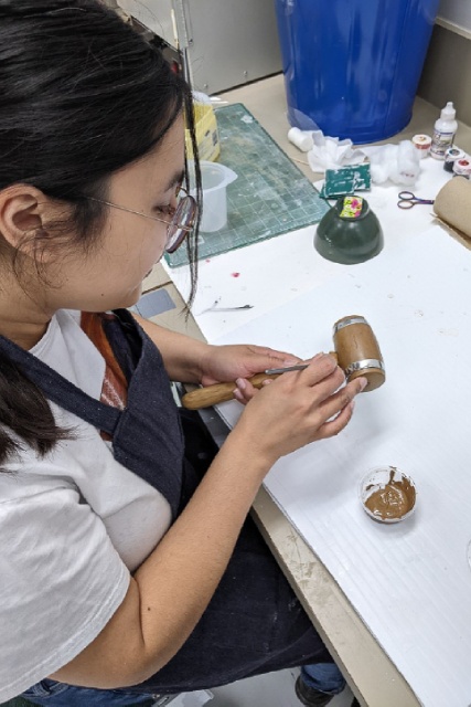 Une personne peint la reproduction d'un artéfact dans un laboratoire