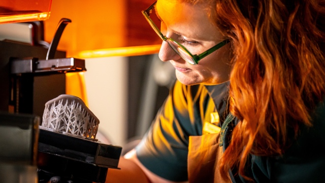 Une personne en uniforme retire un modèle d'une imprimante 3D