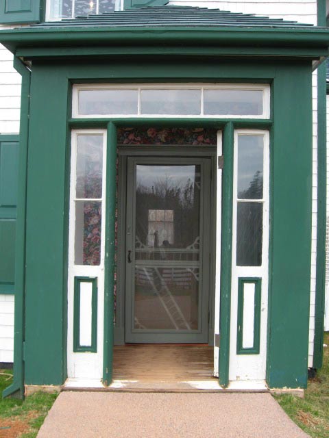 The main entrance of a historic building shows a rather wide door frame and the doorstep at the same height as the path leading to it. 