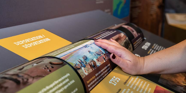 La main d'un visiteur interagit avec une roue qui comporte du texte, faisant partie de l'exposition.
