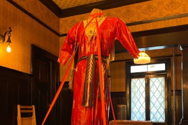 Une robe rouge faite de ruban adhésif exposée dans une grande pièce.