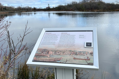 Un vue sur l'eau et un panneau d'interprétation extérieur racontant l'histoire de Baawaating, «le lieu des rapides».
