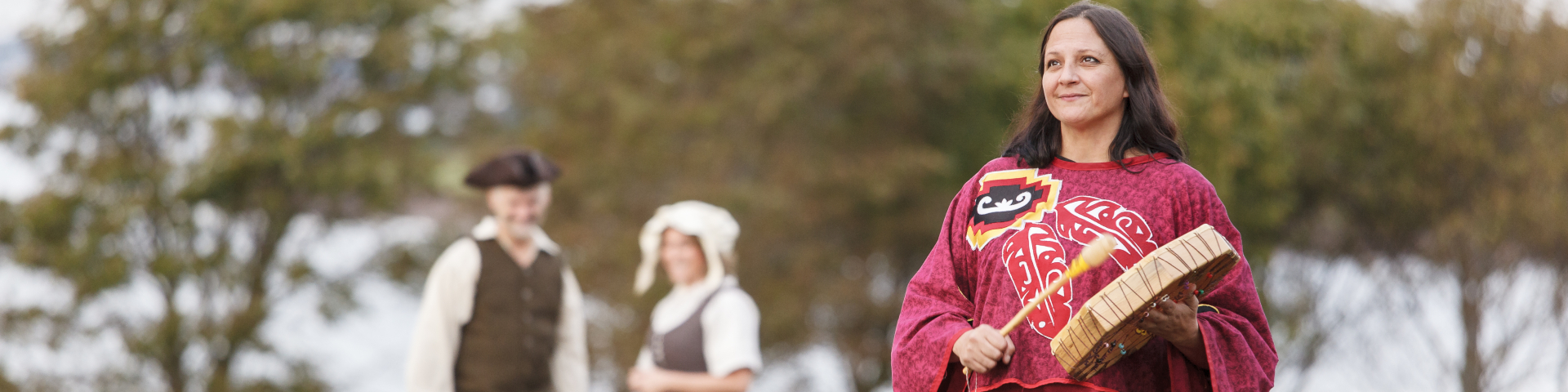 Des animateurs vêtus à la façon des colons acadiens et une femme Mi’kmaq reconstituent un moment historique sur une colline surplombant l’embouchure d'une rivière