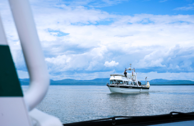 A photo is taken from aboard a boat on the water of another boat that is nearby.