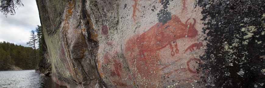 Ce pictogramme en forme de bison apparaît sur la paroi d’une falaise au-dessus des eaux du lac Artery. Il est de couleur rougeâtre. 