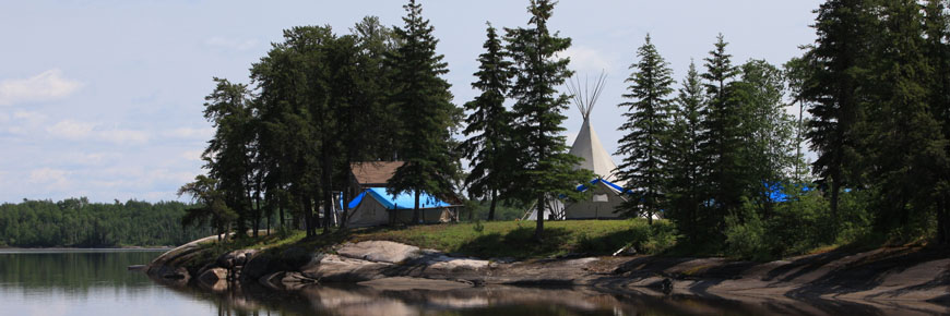 Des tentes et un tipi sont dressés entre des arbres à feuilles persistantes au bord du lac Weaver.
