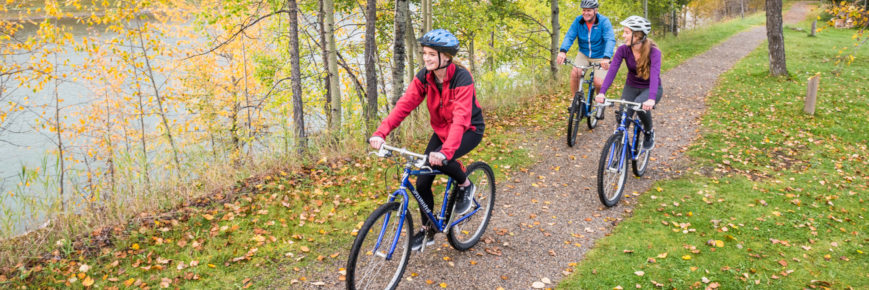 Three people cycling beside a river.