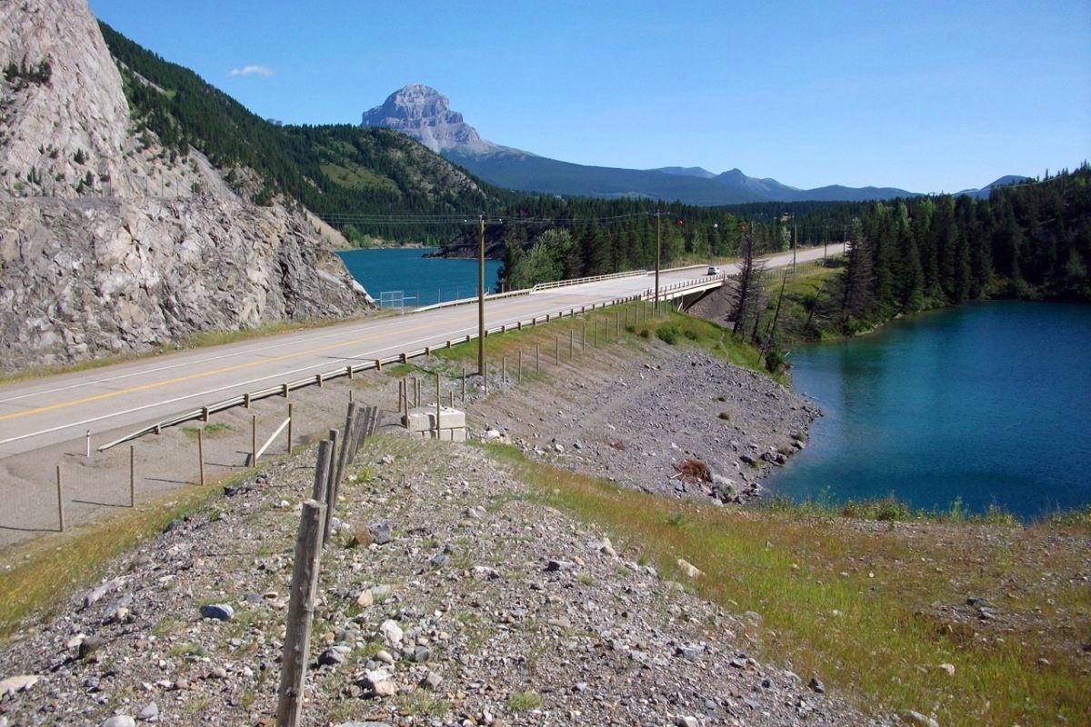 Une route s’étend sur un plan d’eau entouré d’un paysage montagneux.