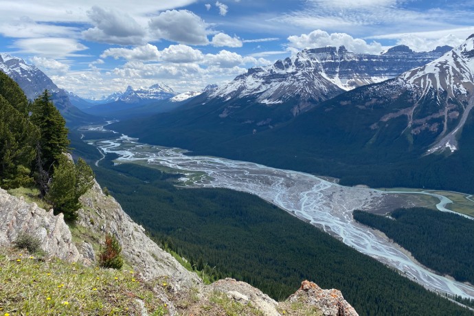 An aerial view of a snow-capped mountain landscape with a tributary river system running through it.