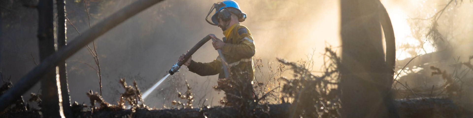 A fire crew member sprays down a burning log with a fire hose during the Chetamon wildfire in Jasper National Park
