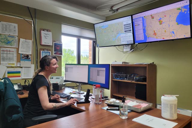 Wood Buffalo National Parks’ fire radio operator, is shown at her computer while coordinating multiple wildfires with fire management specialists in-the-field 
