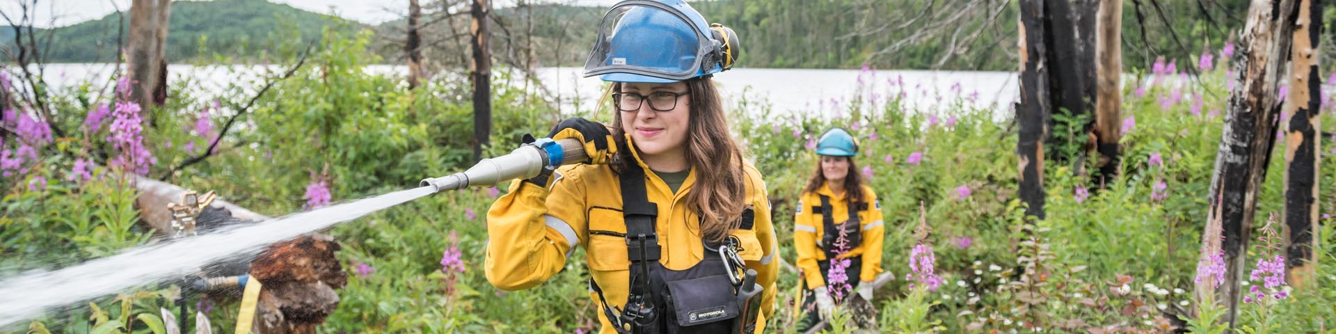 	Une des membres de l'équipe des incendies arrose le bois d'un site de brûlage dirigé à Hattie Cove, au parc national Pukaskwa. 