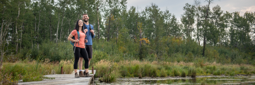 Un homme et une femme observent un milieu humide à partir d’une plateforme de bois.