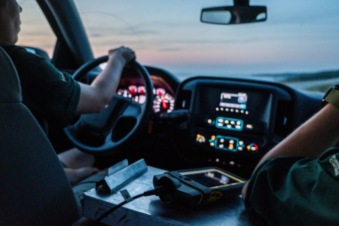 A close up of two Parks Canada staff sitting in the interior of a truck at dusk.