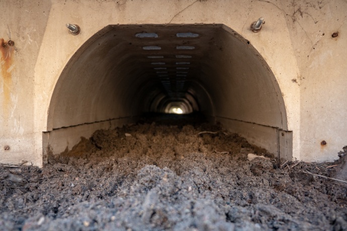 A close up of a small cement tunnel with an earth floor.