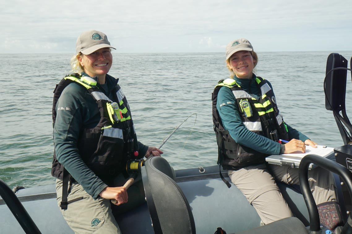Deux membres du personnel de Parcs Canada à bord d’un bateau enregistrent des données lors d’un relevé de mammifères marins.