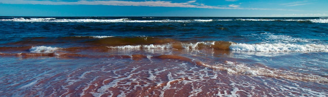 A view of Pituamkek’s shoreline, as the low tide rolls in onto the reddish-brown, smooth sand. 