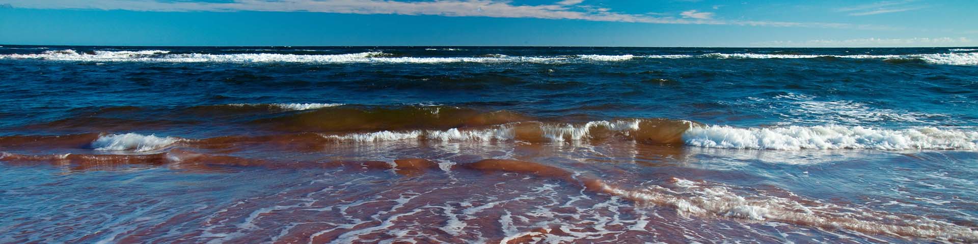 Vue du littoral de Pituamkek. La marée basse déferle sur le sable lisse brun rougeâtre