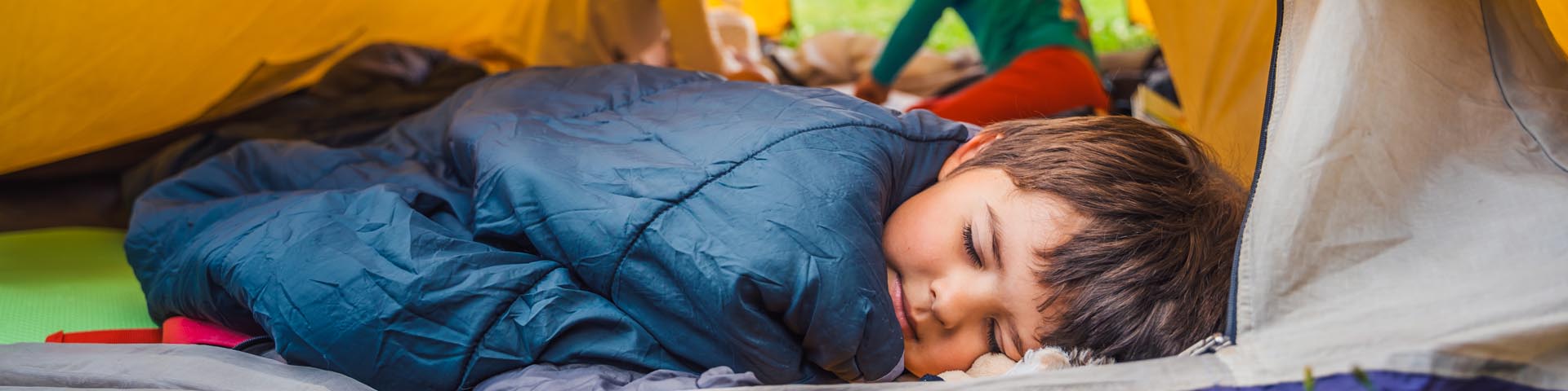 A young child, asleep in a tent.