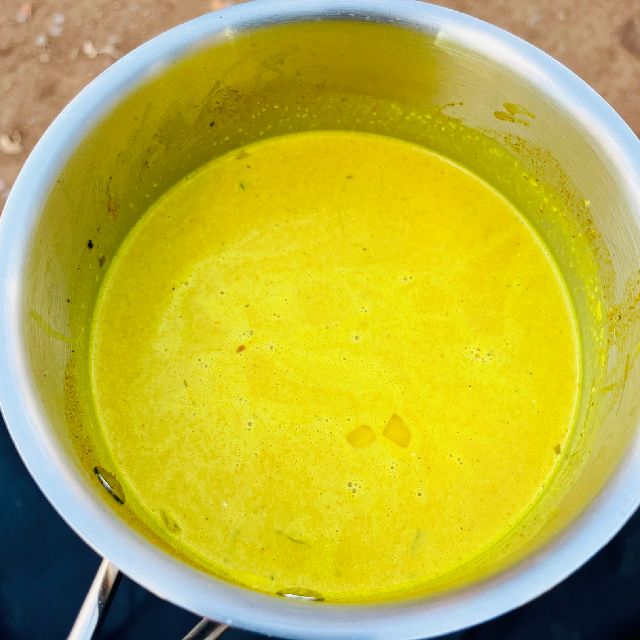 A pot filled with the bright yellow sauce that forms the base of the dahl.