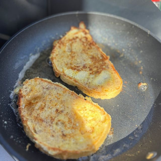 Bread dipped in the egg mixture frying in a buttered pan until golden.