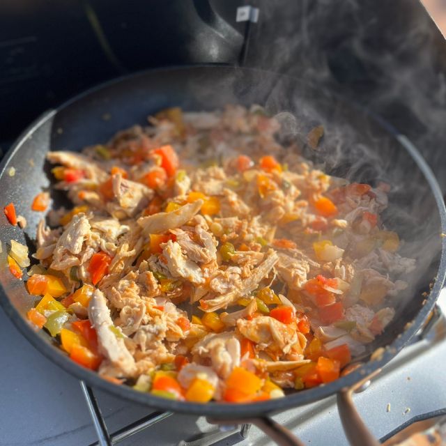 Vegetables, shredded chicken, and salsa simmering together in a pan.