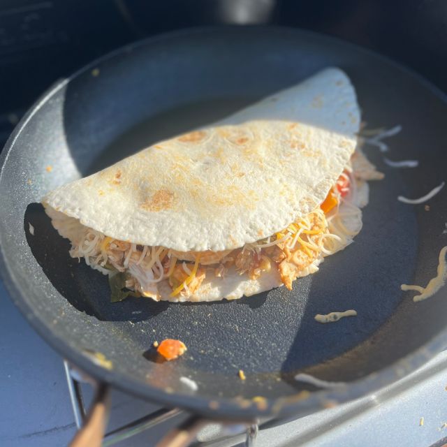 A folded tortilla filled with the mixture and cheese cooking in a new pan with a little oil.