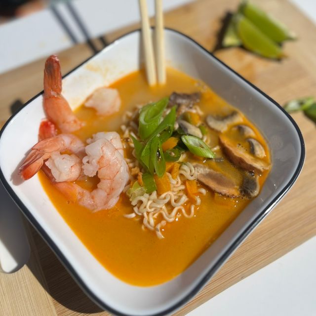 Ramen served in a bowl and topped with cooked shrimp and sliced green onions.