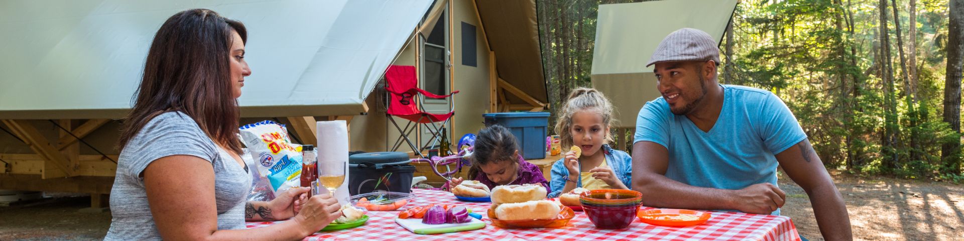 A family having lunch at a picnic table on their campsite.