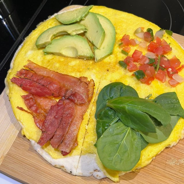 The tortilla cut from the center to the edge and divided into four sections with bacon, avocado, salsa, and spinach in separate sections.