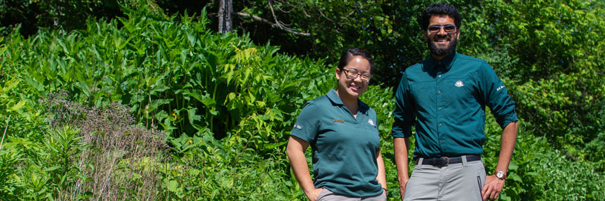 A man and a woman in Parks Canada uniforms standing in front of a garden.
