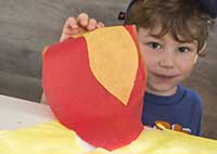 Young boy holding up artwork.