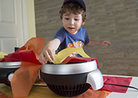 Young boy placing tissue paper on fan.