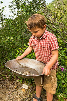 Un enfant cherche de l'or dans une batée