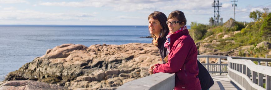 Deux visiteurs observent les baleines depuis le rivage au parc marin du Saguenay—Saint-Laurent.