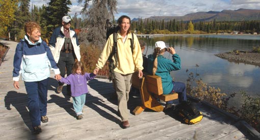 Six visitors on a wooden sidewalk at the edge of Kathleen Lake.