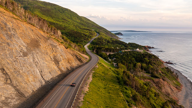 An aerial view of the cabot trail, a road nestled between the sea and cliffs in Cape Breton Highlands National Park.