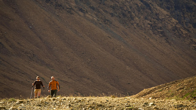 Two adults walk in the Tablelands, a backcountry landscape, in Gros Morne National Park.