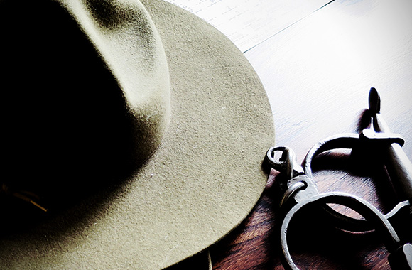 A North West Mounted Police hat with historic handcuffs on a wooden table