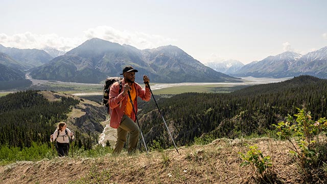 Two hikers travelling up a mountain in Kluane.