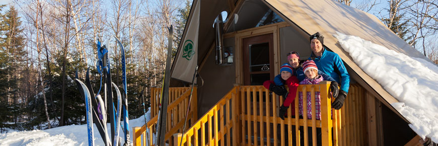 A family in front of an oTENTik in the winter.