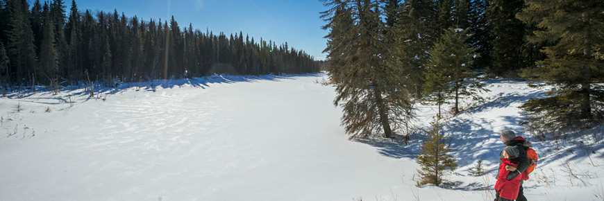 Deux visiteurs font de la raquette en bordure d’un lac.