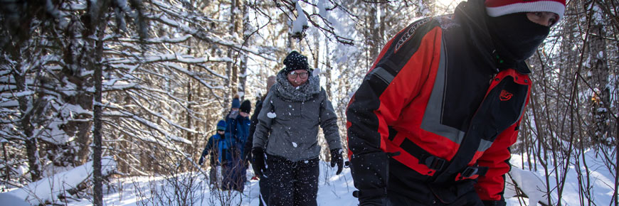 Adults snowshoeing through Riding Mountain National Park.