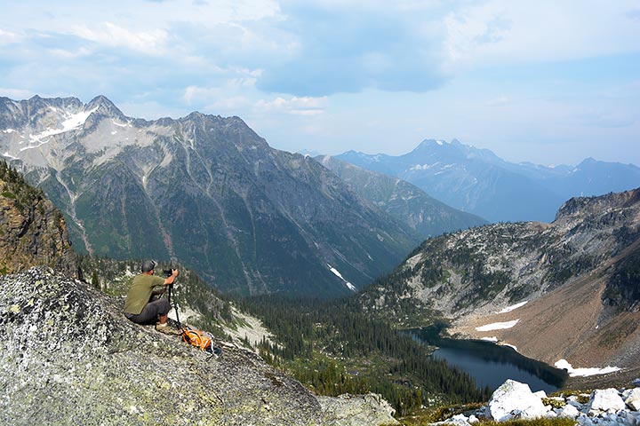 A hiker takes a picture of the mountainous landscape surrounding Jade Lake.