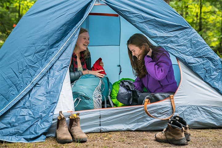 Two girls laugh while setting up their tent on Beausoleil Island.