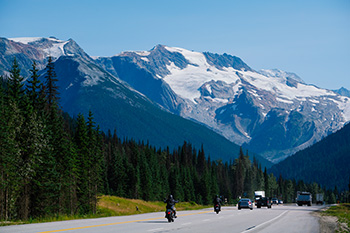 Des voitures roulent sur la route Transcanadienne avec des montagnes au premier plan