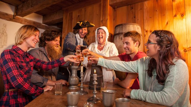 Four visitors discover the taste of Fortress Rum and its story in a period tavern with costumed guides at the Fortress of Louisbourg.
