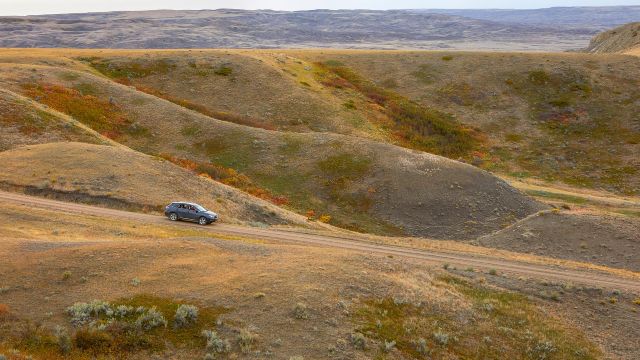 A vehicle driving on a scenic road in Grasslands National Park.